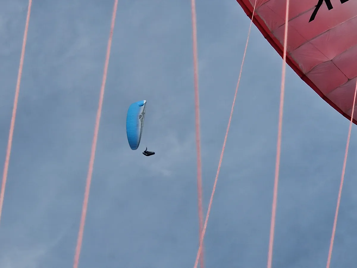 A blue paraglider in flight